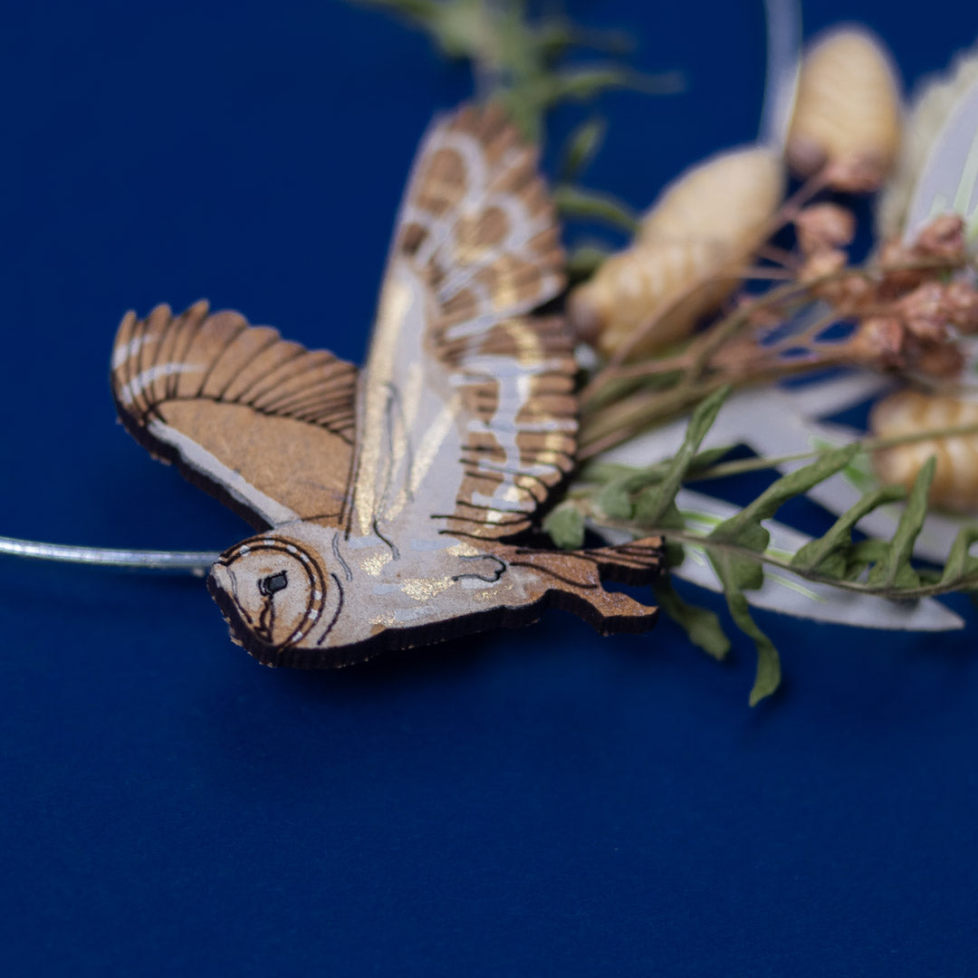Wooden butterfly ornament on a branch with dried leaves against a blue background