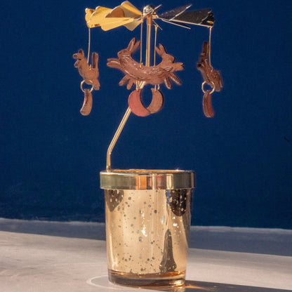 Decorative metal candle holder with spinning animals on a blue background