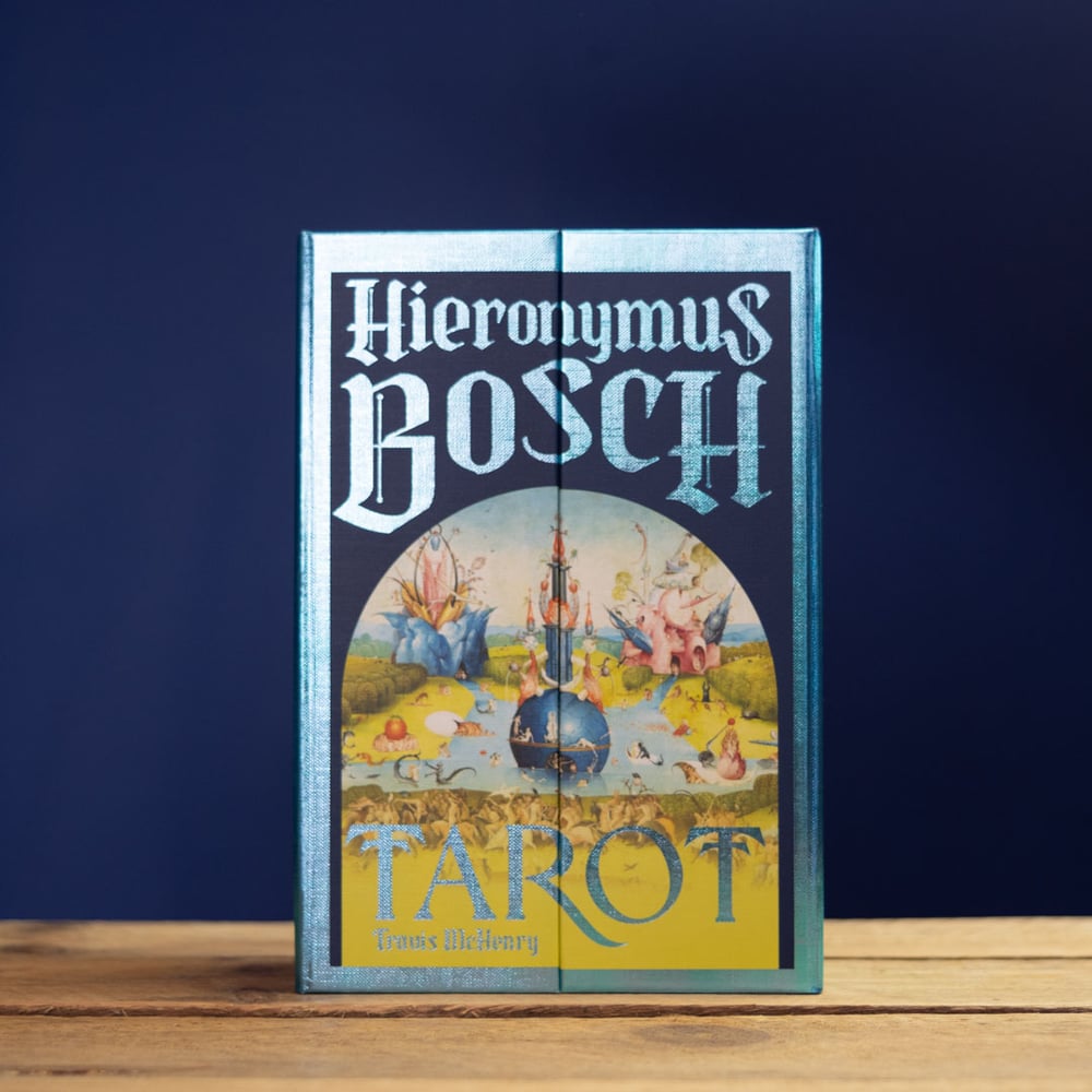 Hieronymus Bosch Tarot card set packaging on a wooden surface with a dark blue background