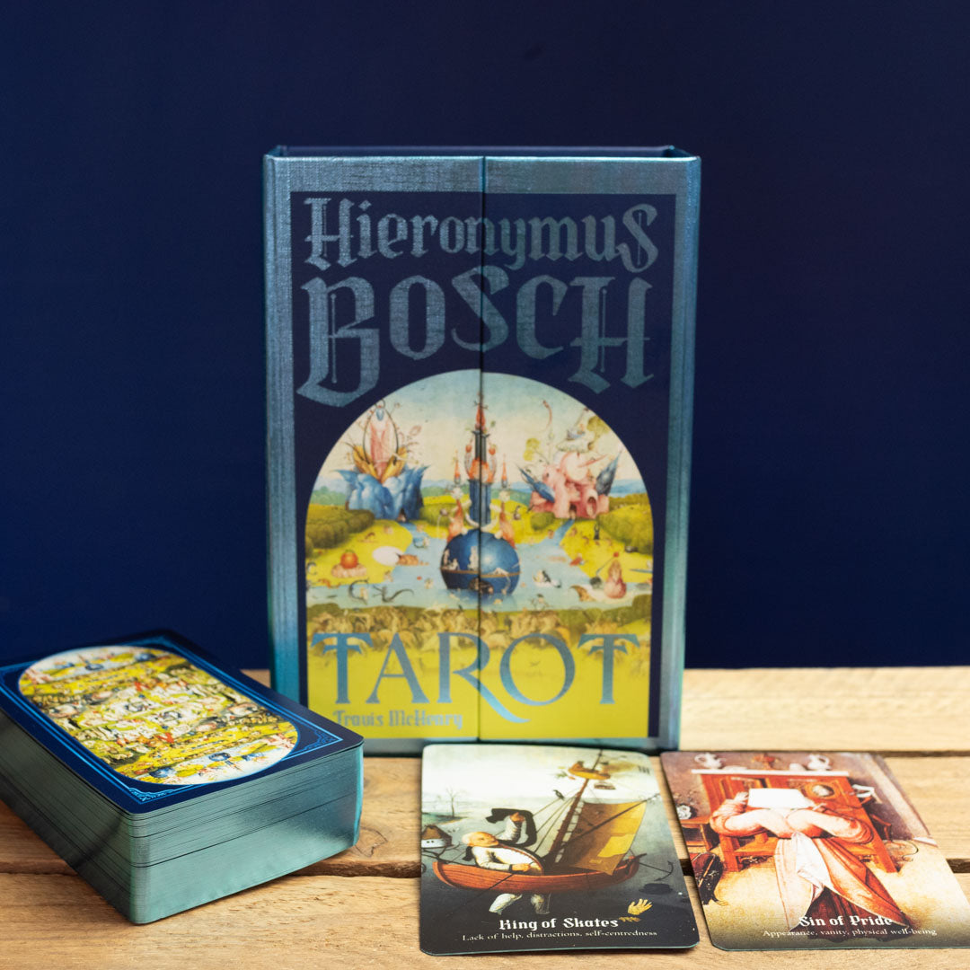 Hieronymus Bosch Tarot card set with tarot cards displayed on a wooden surface against a dark blue background.