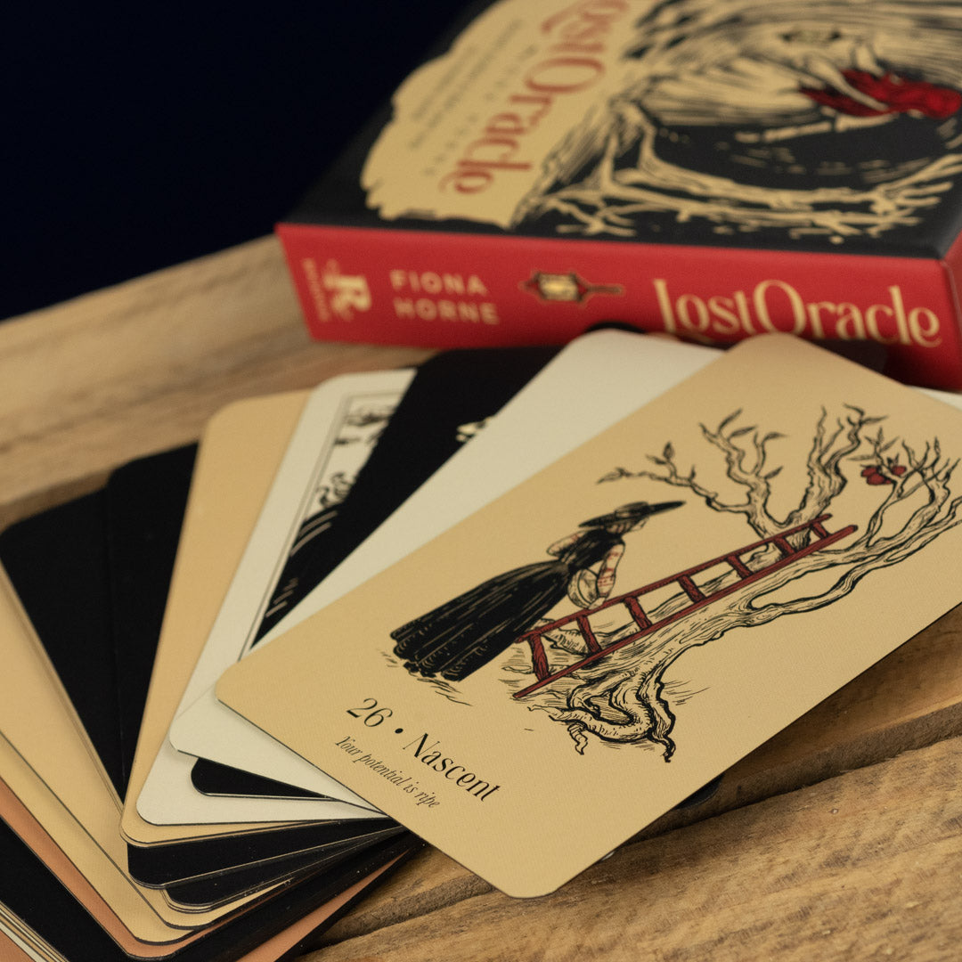 Cards from the 'Lost Oracle' with a box titled 'Lost Oracle' in the background on a wooden surface.