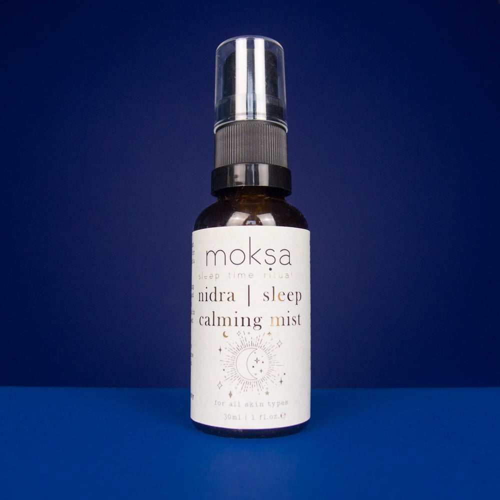 Bottle of moksa nidra sleep calming mist on a blue background