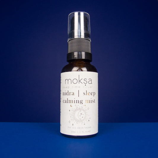 Bottle of moksa nidra sleep calming mist on a blue background