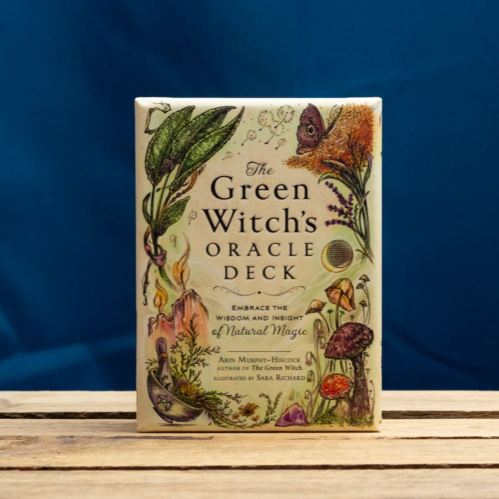 The Green Witch's Oracle Deck on a wooden surface with a blue background