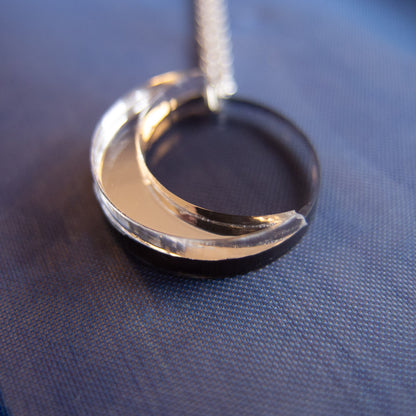 Gold crescent moon pendant on a chain against a blue fabric background