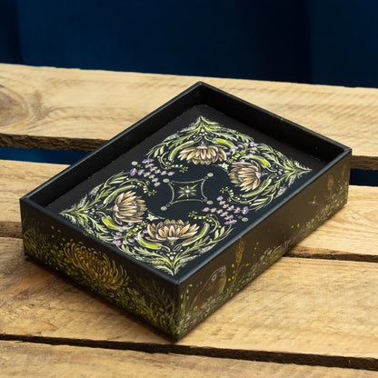 Decorative black box for Green Witches oracle Deck with floral design on a wooden surface