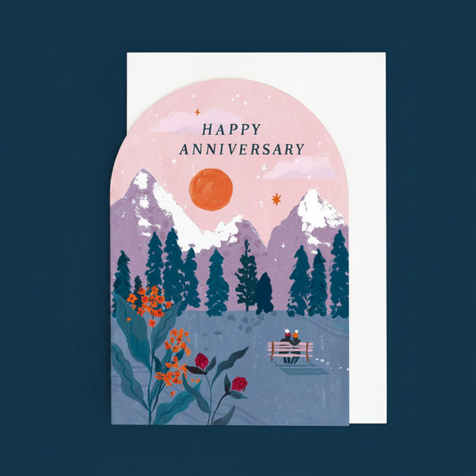 Greeting card with a mountain landscape, couple on a bench, and 'Happy Anniversary' text.