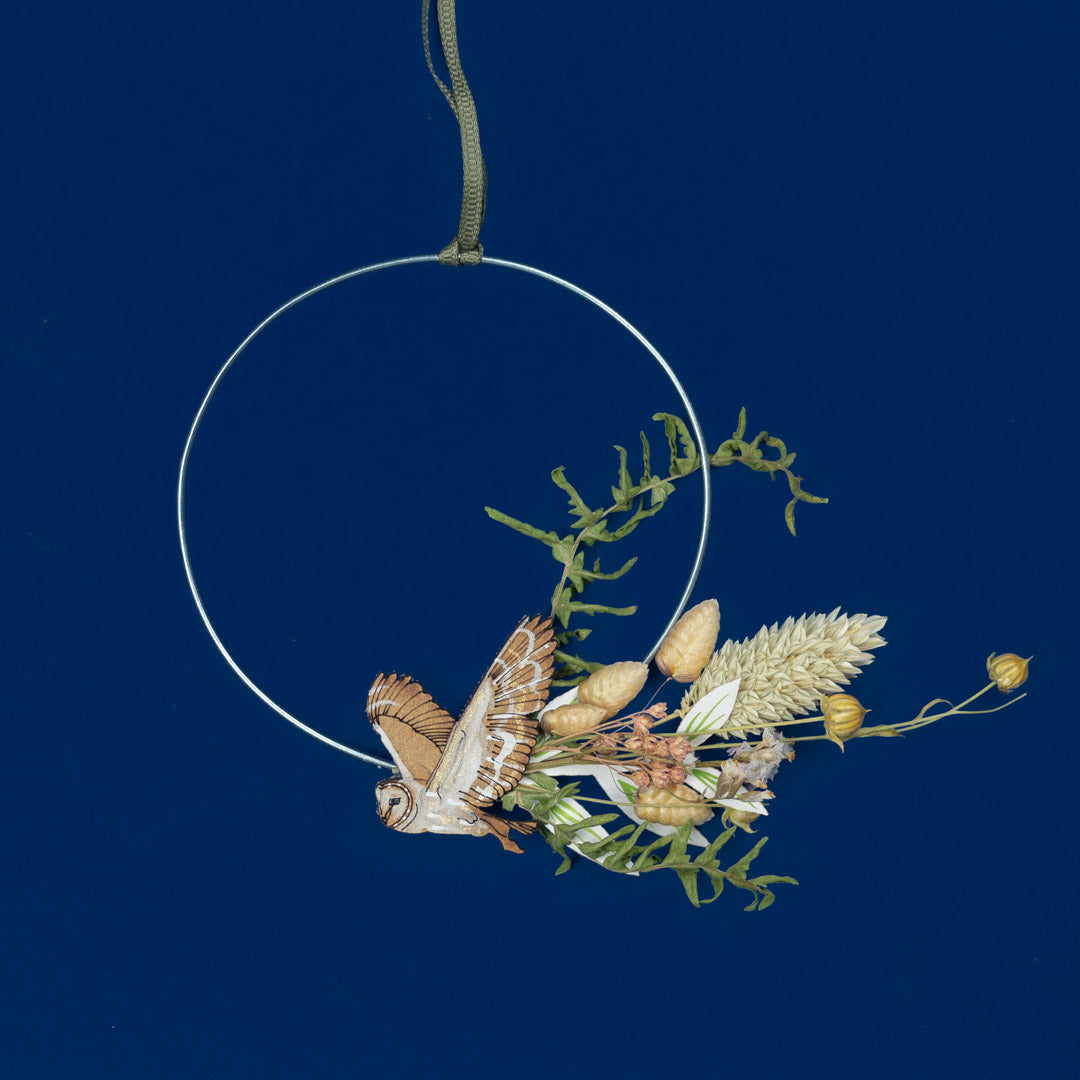 Decorative wreath with owl and plants on a dark blue background