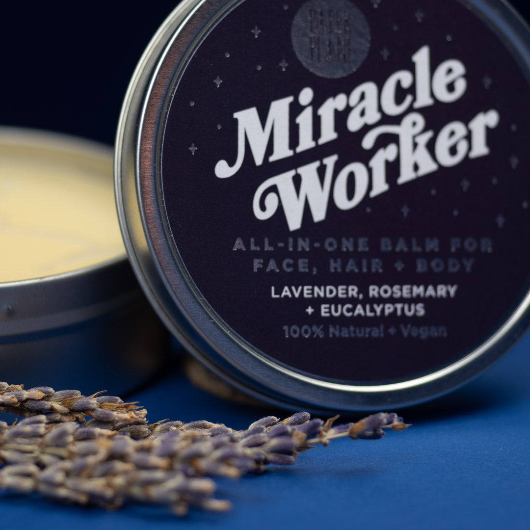 Tin of 'Miracle Worker' all-in-one balm with lavender and rosemary, on a blue background.