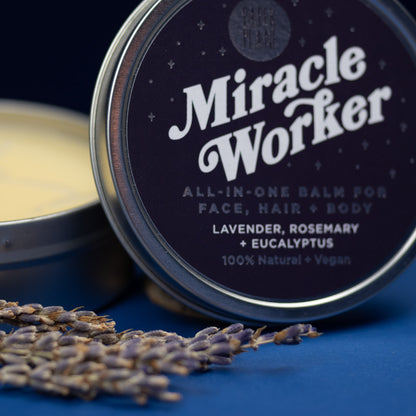 Tin of 'Miracle Worker' all-in-one balm with lavender and rosemary, on a blue background.