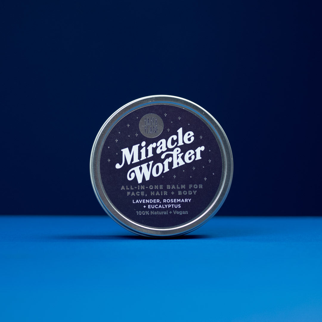 Tin of 'Miracle Worker' all-in-one balm on a blue background