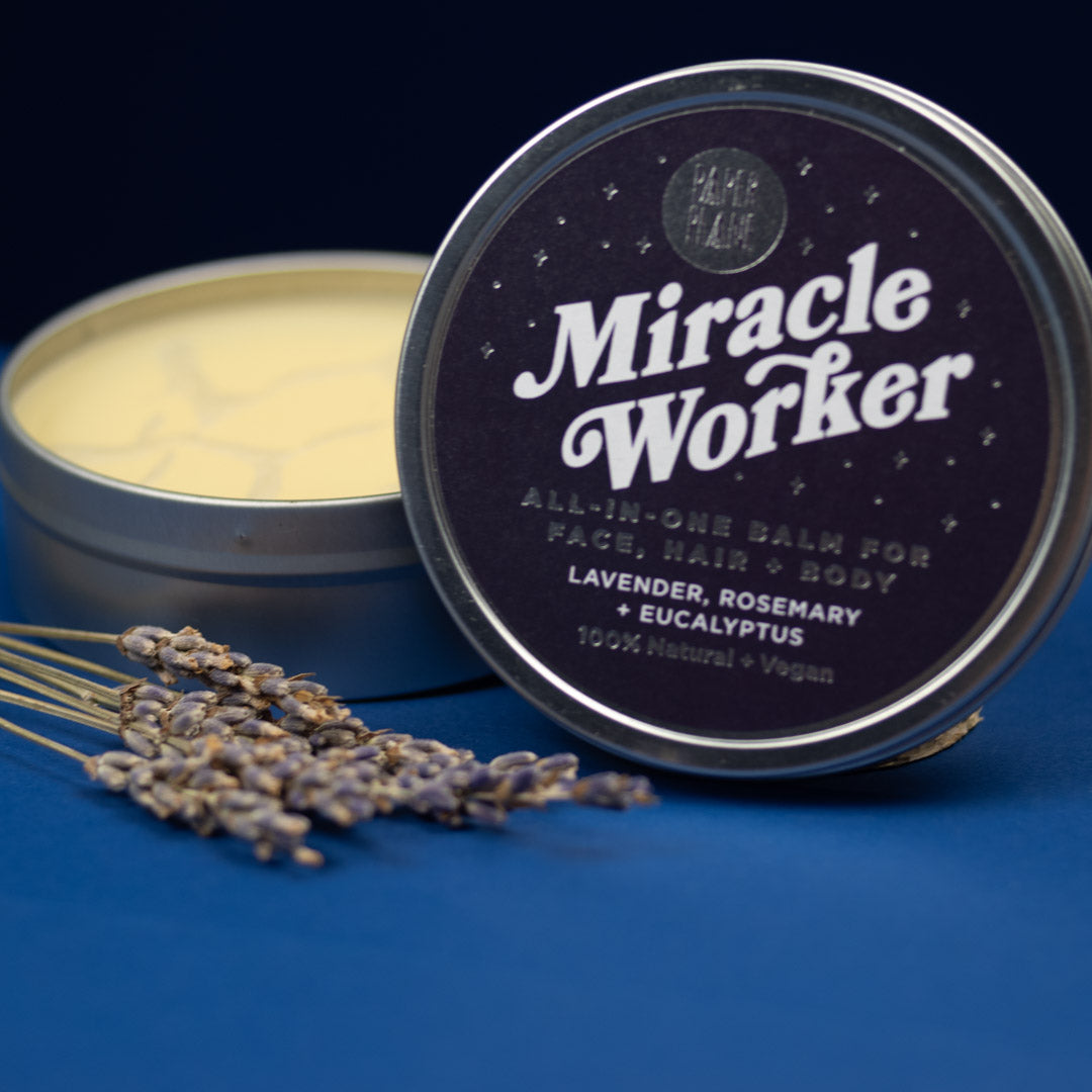 Tin of 'Miracle Worker' all-in-one balm with lavender and rosemary on a blue background