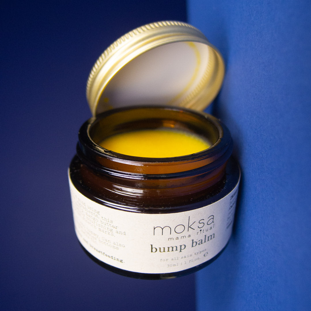 Open jar of moksa bump balm against a blue background