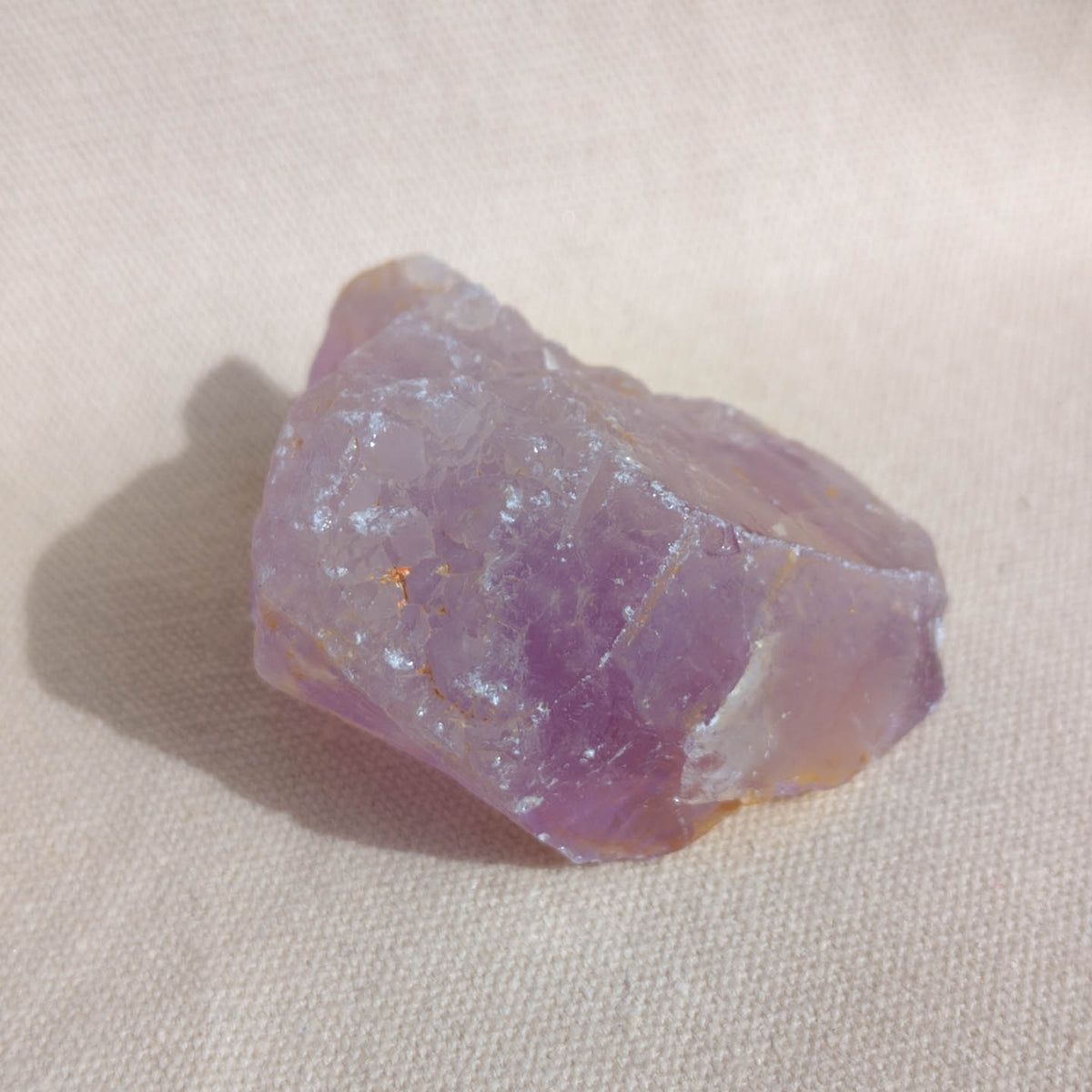 Raw amethyst crystal on a beige fabric background