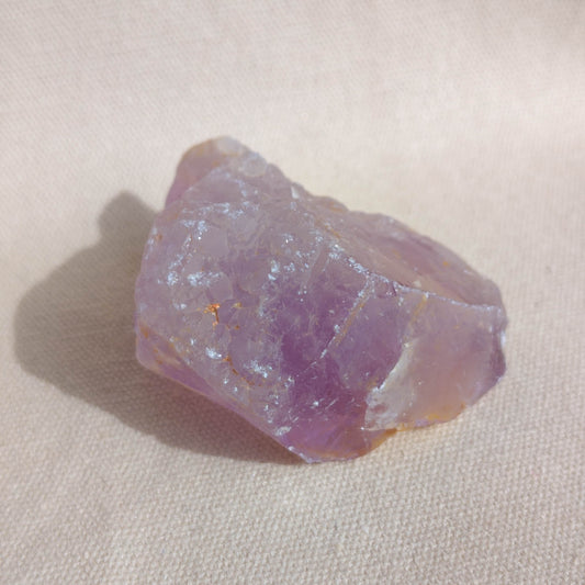 Raw amethyst crystal on a beige fabric background