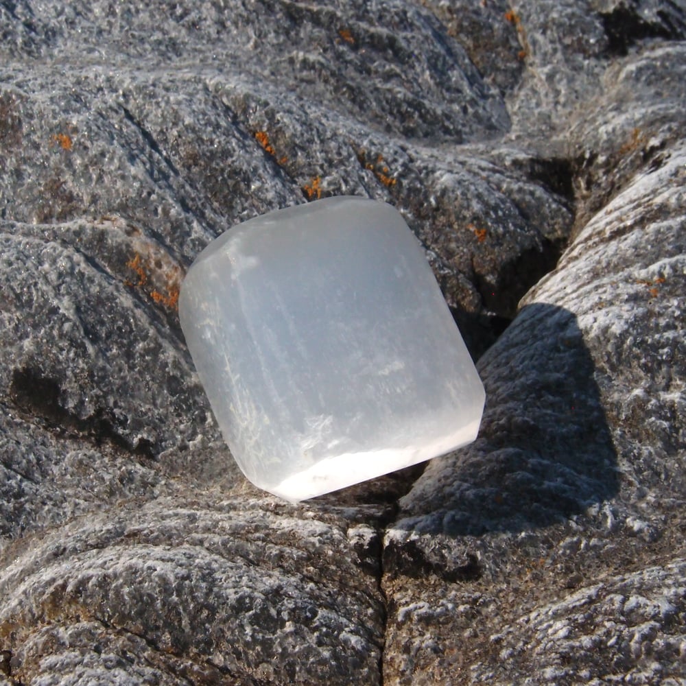Clear selenite crystal stone on a rocky surface