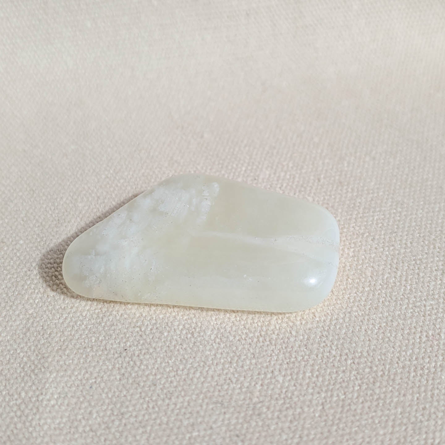 Serpentine Jade gemstone on a light pink fabric background