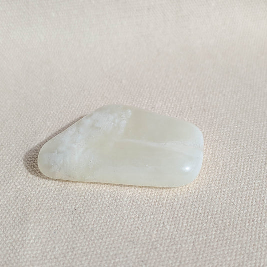 Serpentine Jade gemstone on a light pink fabric background