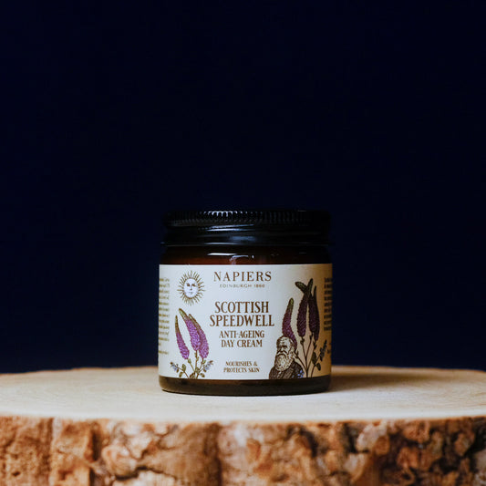 Jar of Napiers Scottish Speedwell Anti-Ageing Day Cream on a wooden surface with a dark background