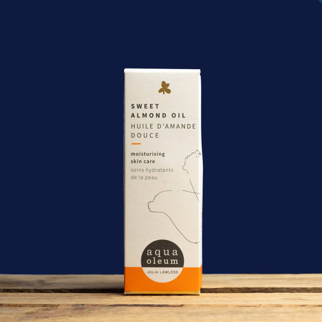 Box of Sweet Almond Oil by aqua oleum on a wooden surface with a dark blue background