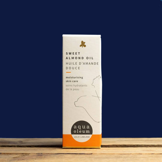 Box of Sweet Almond Oil by aqua oleum on a wooden surface with a dark blue background