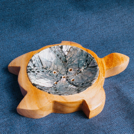 Wooden turtle soap dish with a metallic interior on a blue fabric background