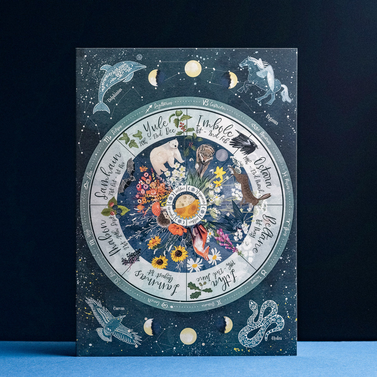 Decorative circular design greeting card with animals, flowers, and celestial elements on a dark blue background.